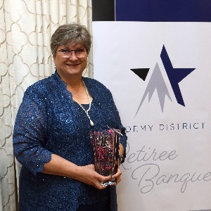 Karla Tate smiles a for picture with her vase at the 2023 Retiree Banquet